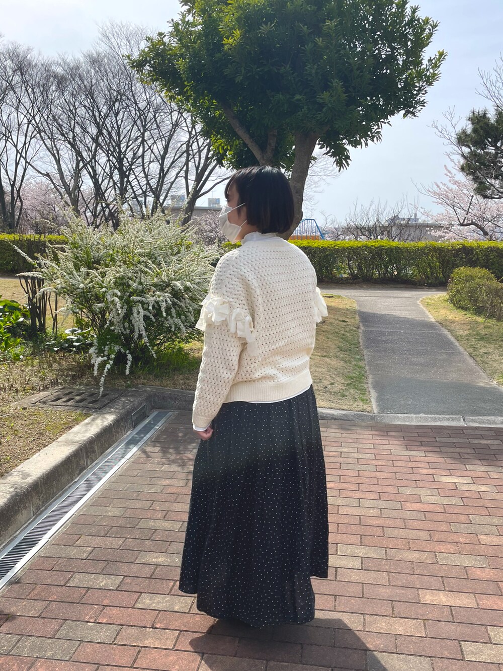 ホワイト系のニット/セーター、ホワイト系のTシャツ/カットソー、ブラック系のスカートを着用したレディースの春コーディネートの2枚目の写真