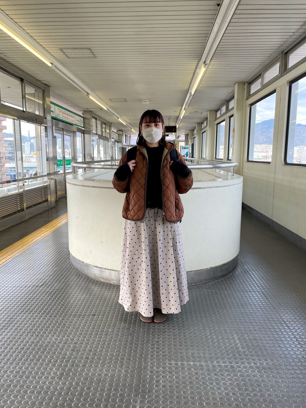 ブラウン系のダウンジャケット/コート、ブラック系のバックパック/リュック、ブラック系のシャツ/ブラウスを着用したレディースの冬コーディネートの2枚目の写真