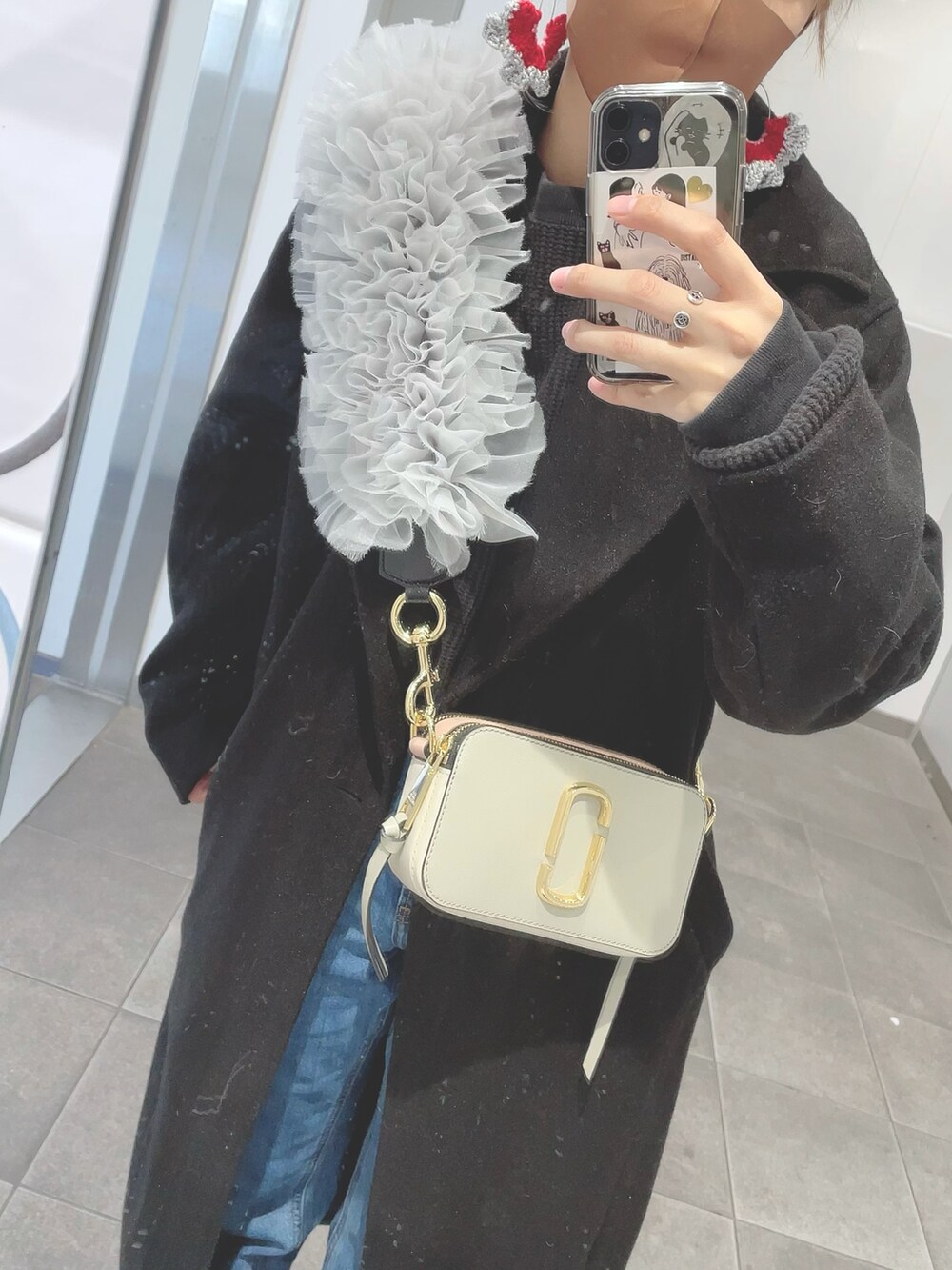 グレー系のショルダーバッグ、ブルー系のデニムパンツ、ブラック系のスニーカーを着用したレディースの冬コーディネートの2枚目の写真