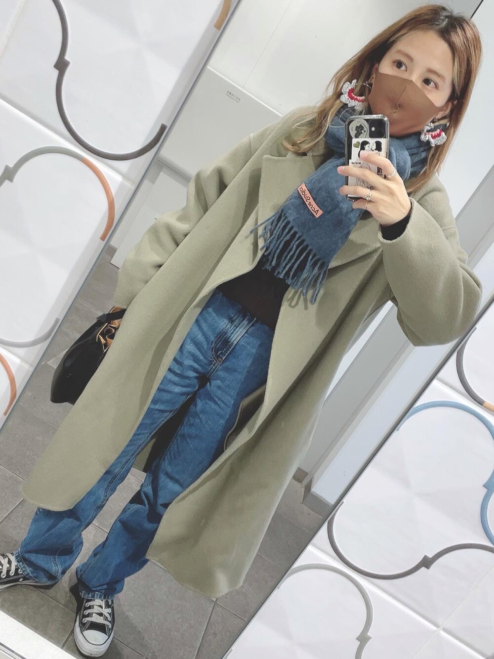 ブルー系のデニムパンツ、ブラック系のトートバッグ、ブルー系のマフラーを着用したレディースの冬コーディネートの2枚目の写真