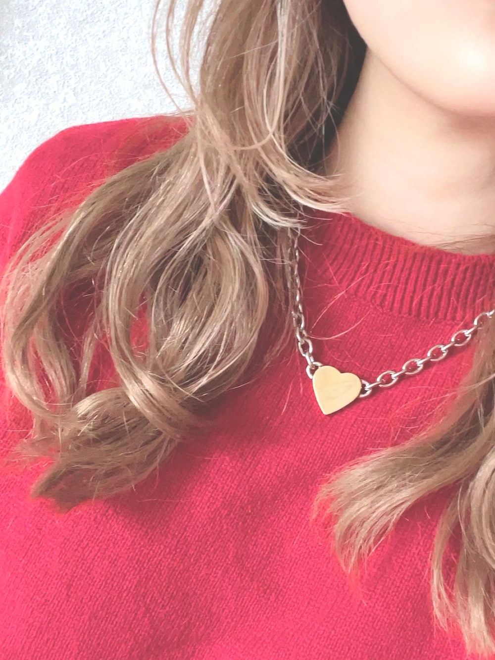 レッド系のニット/セーター、ブルー系のダウンジャケット/コート、ブルー系のデニムパンツを着用したレディースの春コーディネートの3枚目の写真