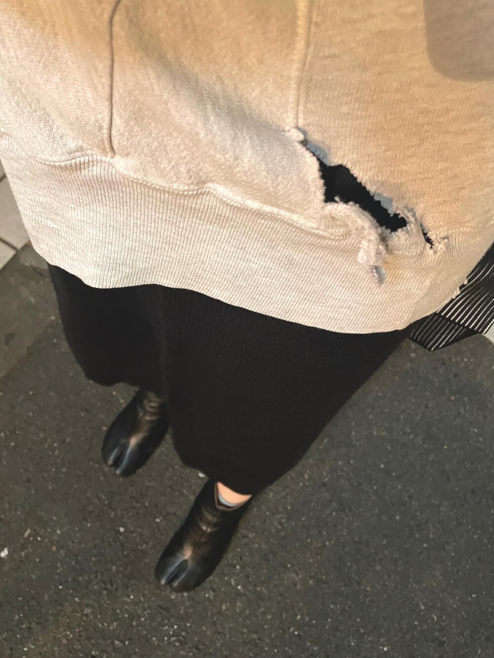 グレー系のスウェット、ブラック系のスカート、ブラック系のブーツを着用したレディースの秋コーディネートの2枚目の写真