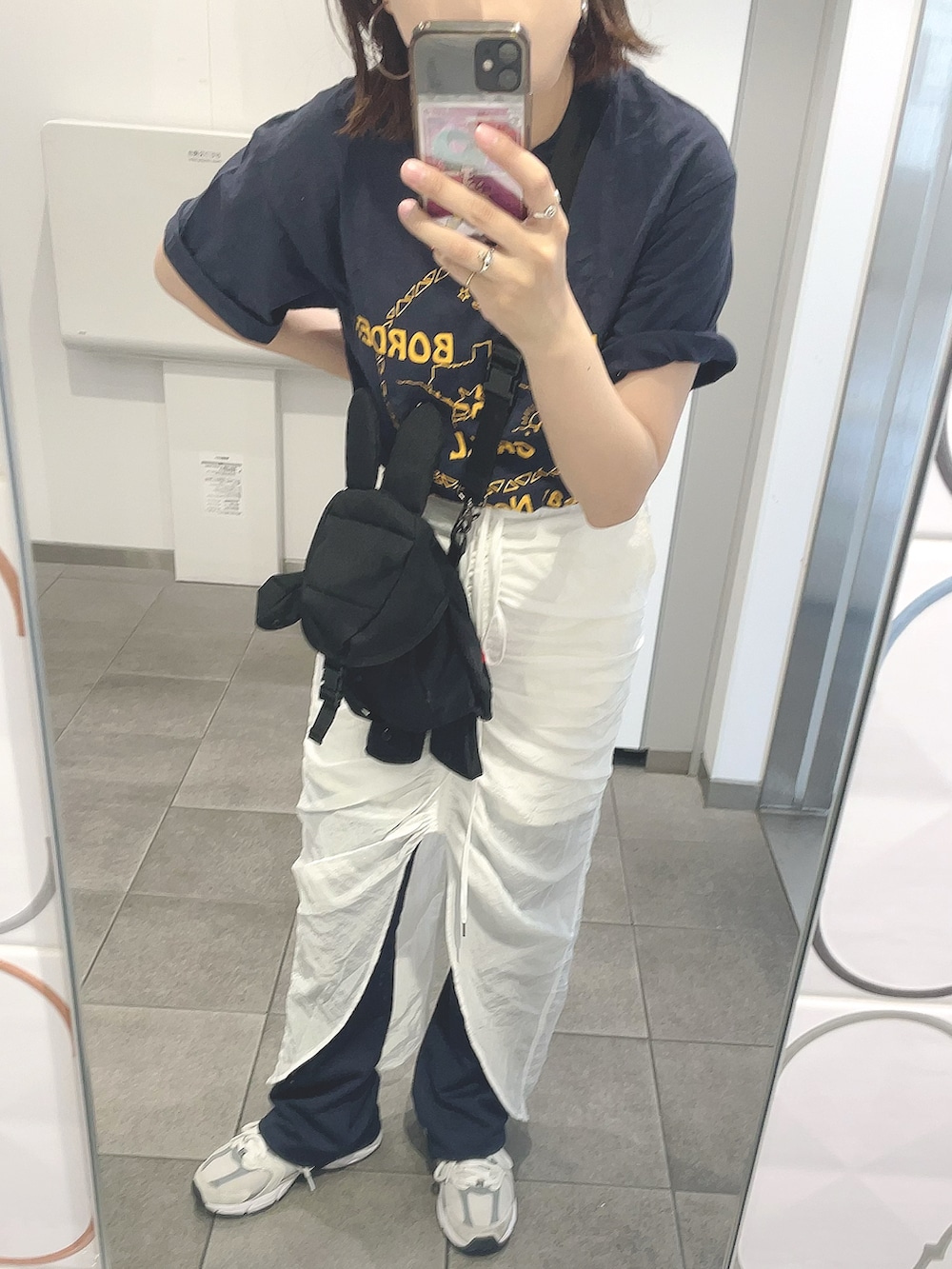 ホワイト系のスカート、ブラック系のショルダーバッグ、グレー系のスニーカーを着用したレディースの夏コーディネートの2枚目の写真