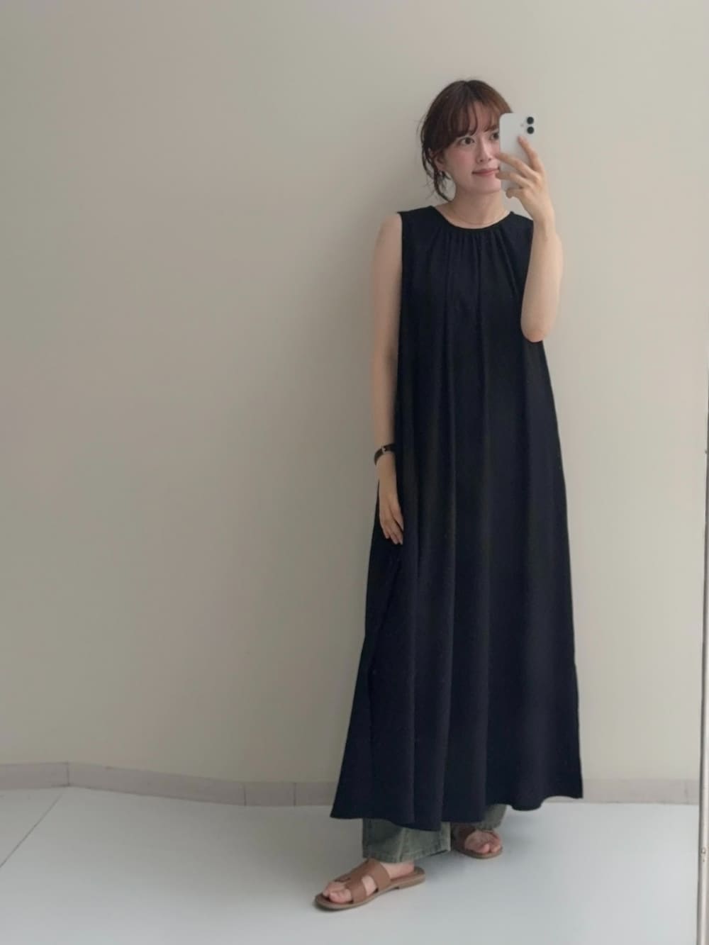 ブラック系のワンピース、ベージュ系のデニムパンツを着用したレディースの夏コーディネートの2枚目の写真