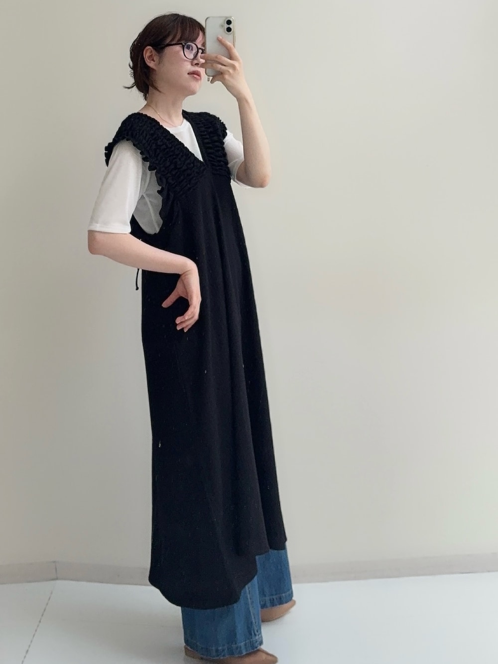 ブラック系のジャンパースカート、ブルー系のデニムパンツ、ホワイト系のTシャツ/カットソーを着用したレディースの春コーディネートの3枚目の写真