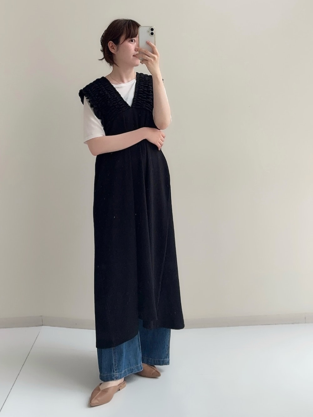 ブラック系のジャンパースカート、ブルー系のデニムパンツ、ホワイト系のTシャツ/カットソーを着用したレディースの春コーディネートの8枚目の写真