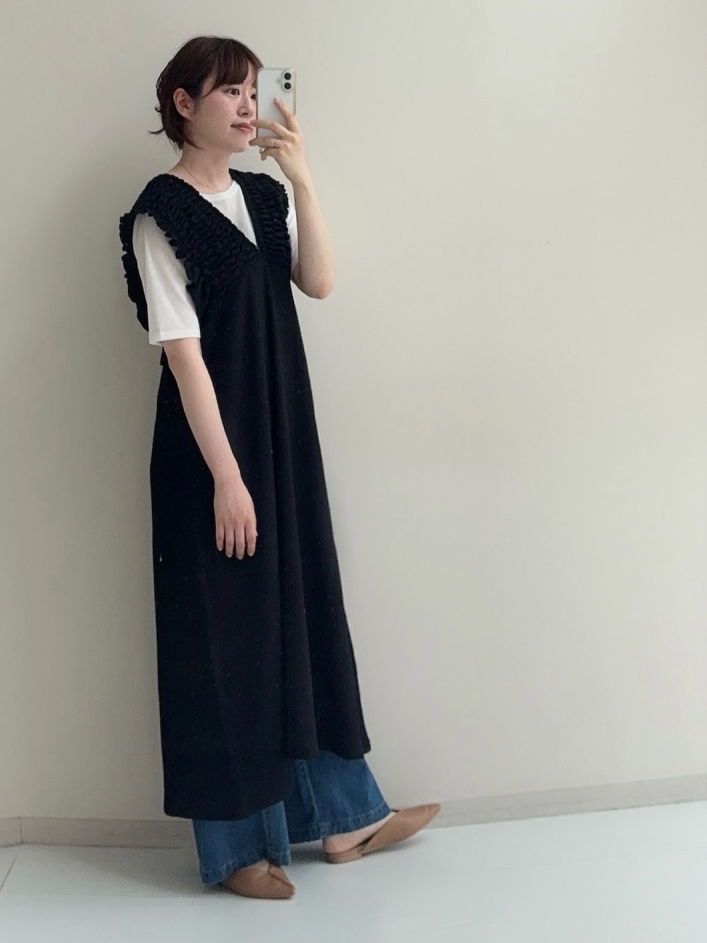 ブラック系のジャンパースカート、ブルー系のデニムパンツ、ホワイト系のTシャツ/カットソーを着用したレディースの春コーディネートの6枚目の写真