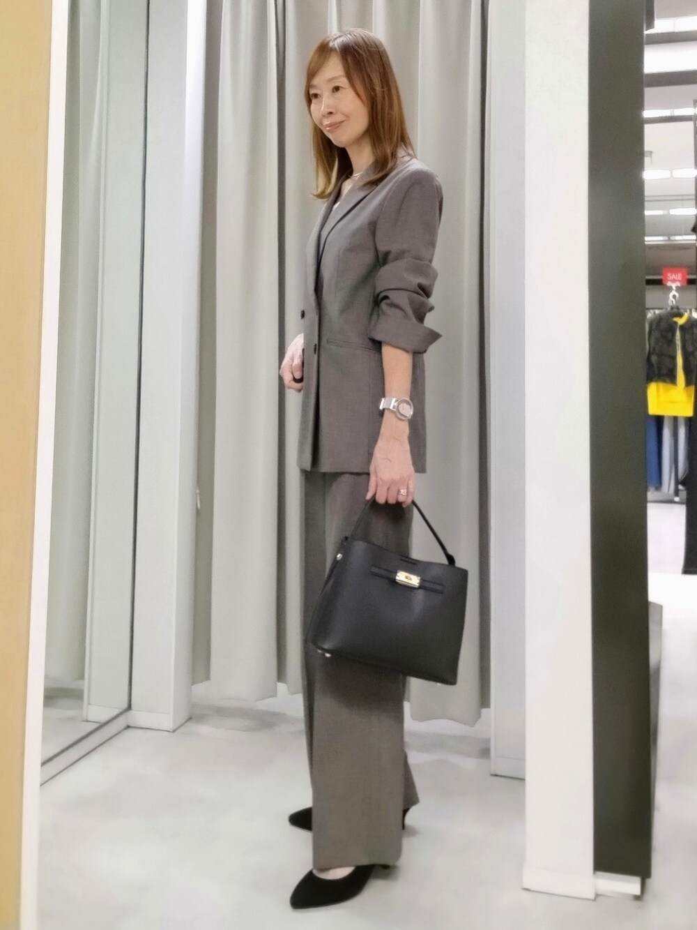 ベージュ系のテーラードジャケット、ベージュ系のその他パンツ、ホワイト系のタンクトップを着用したレディースの秋コーディネートの2枚目の写真