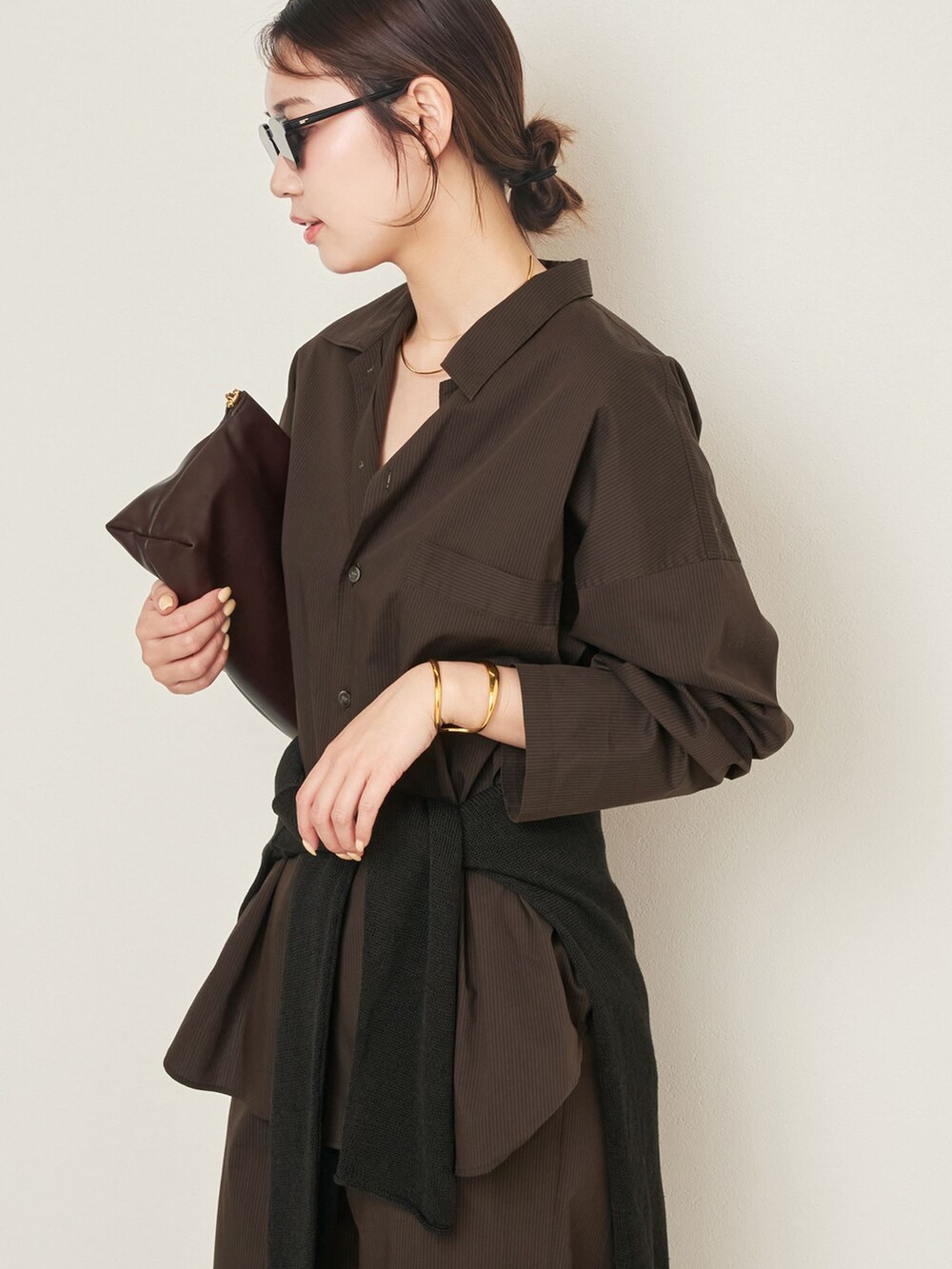 ブラウン系のその他パンツ、ブラウン系のシャツ/ブラウス、ブラウン系のクラッチバッグを着用したレディースの春コーディネートの5枚目の写真