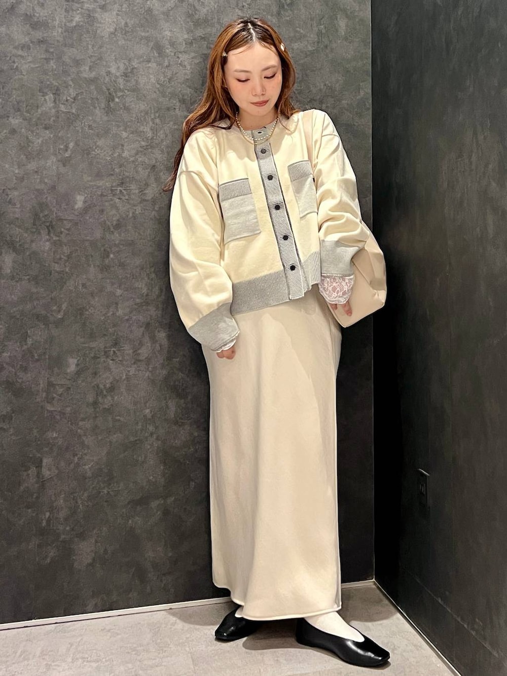 ホワイト系のスカート、ホワイト系のカーディガン/ボレロ、ブラック系のパンプスを着用したレディースの秋コーディネートの2枚目の写真