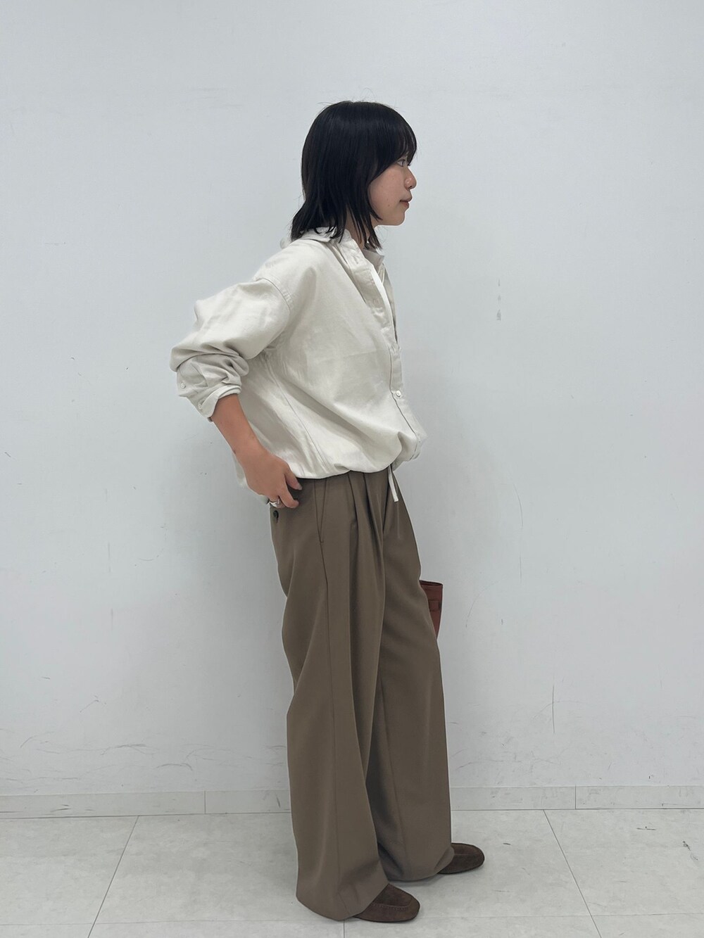 ブラウン系のスラックス、ホワイト系のシャツ/ブラウス、ホワイト系のTシャツ/カットソーを着用したレディースの夏コーディネートの2枚目の写真