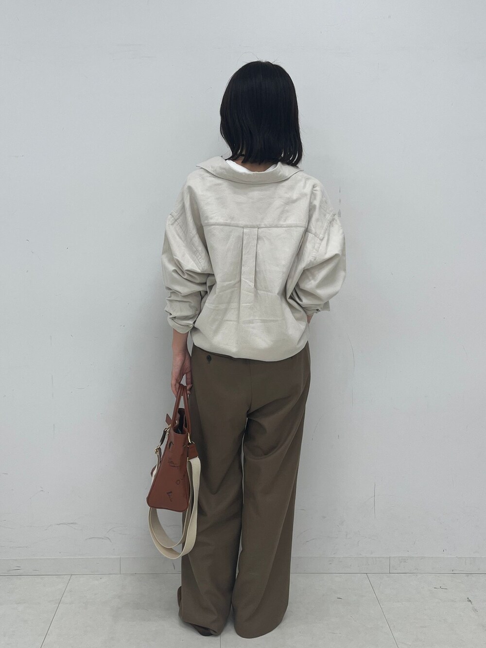 ブラウン系のスラックス、ホワイト系のシャツ/ブラウス、ホワイト系のTシャツ/カットソーを着用したレディースの夏コーディネートの3枚目の写真