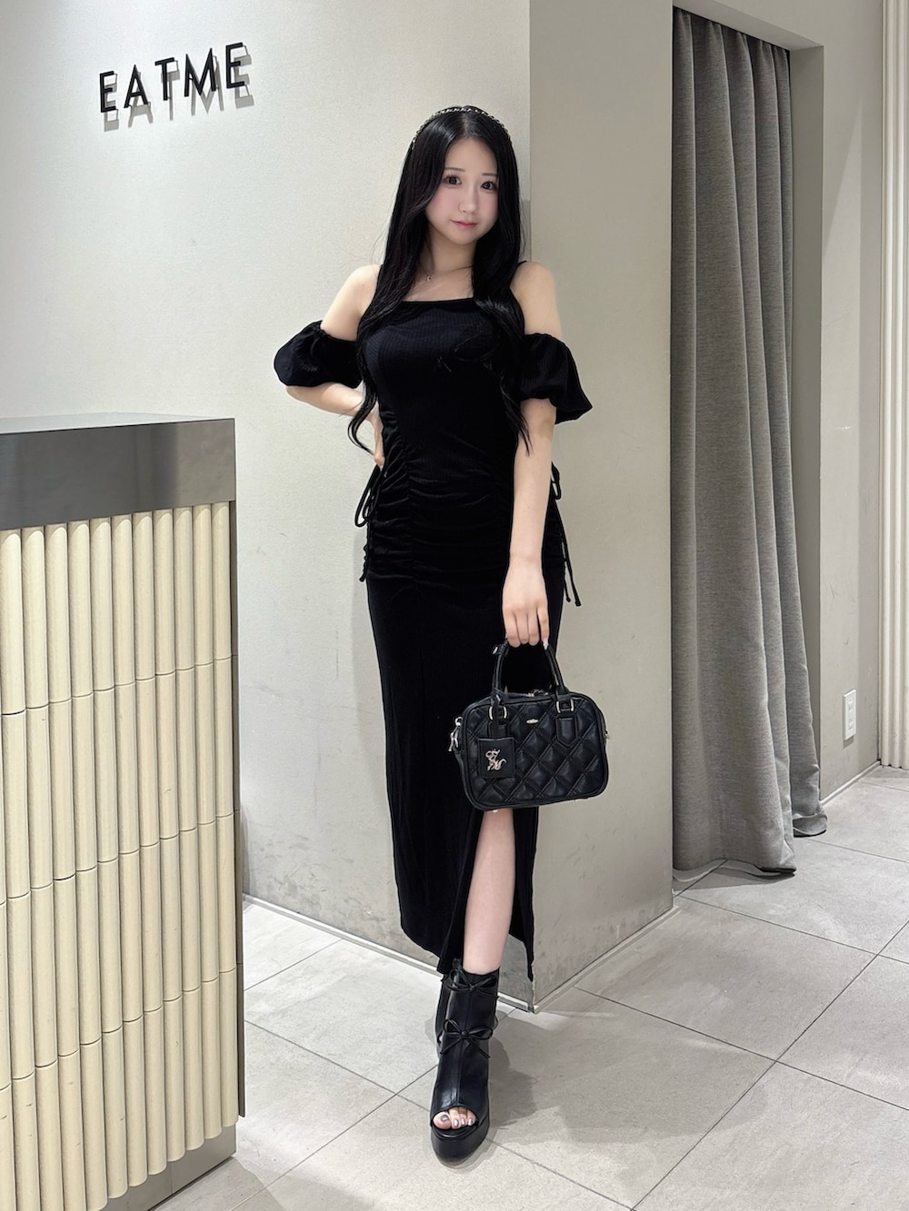 ブラック系のワンピース、ブラック系のハンドバッグ、ブラック系のサンダルを着用したレディースの夏コーディネートの2枚目の写真