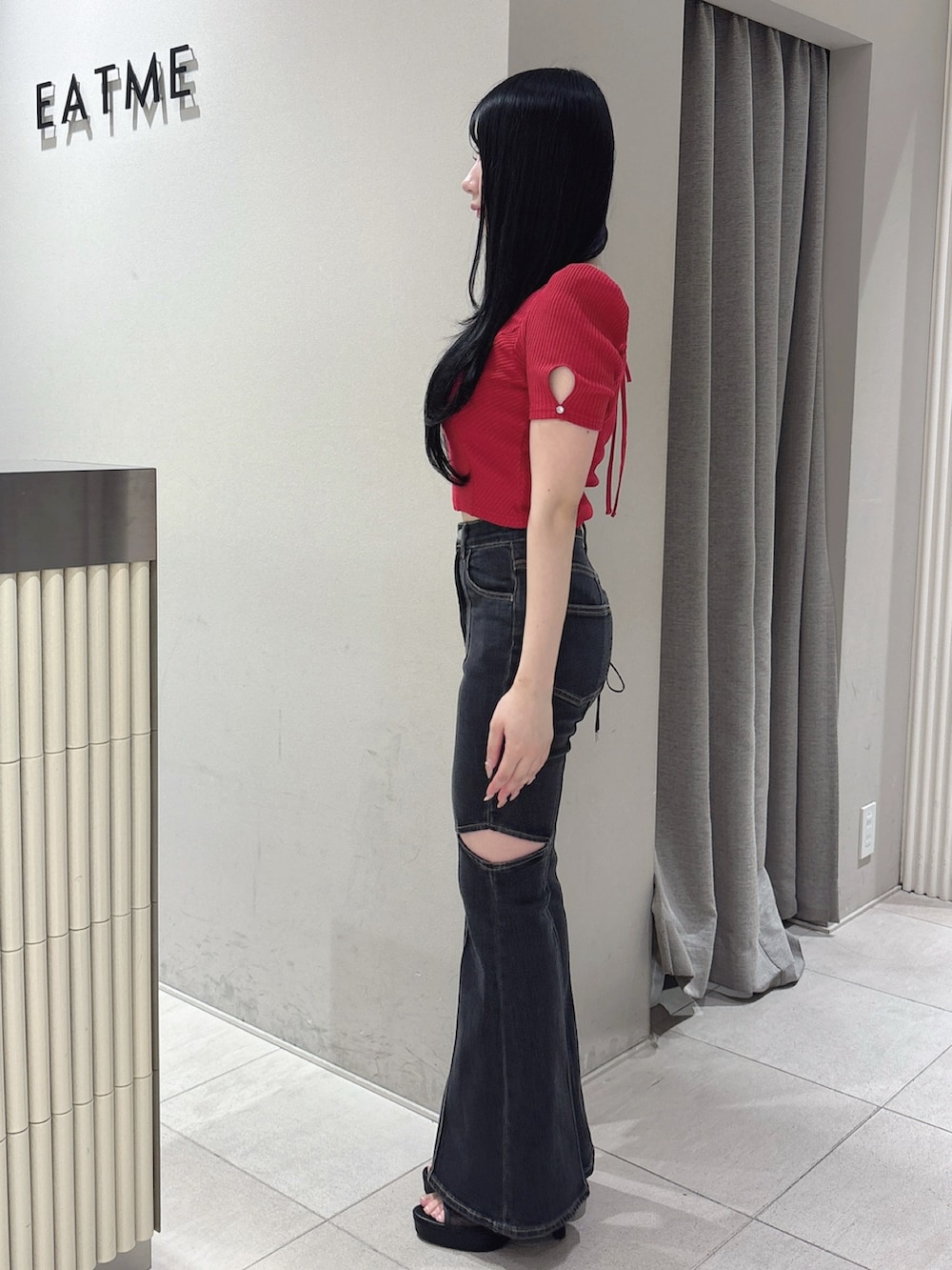ブラック系のデニムパンツ、レッド系のTシャツ/カットソー、ブラック系のサンダルを着用したレディースの春コーディネートの3枚目の写真