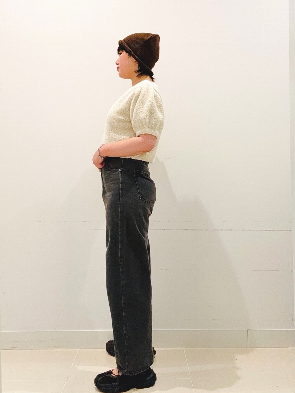 ブラウン系のスニーカー、ホワイト系のニット/セーター、グレー系のデニムパンツを着用したレディースの夏コーディネートの3枚目の写真