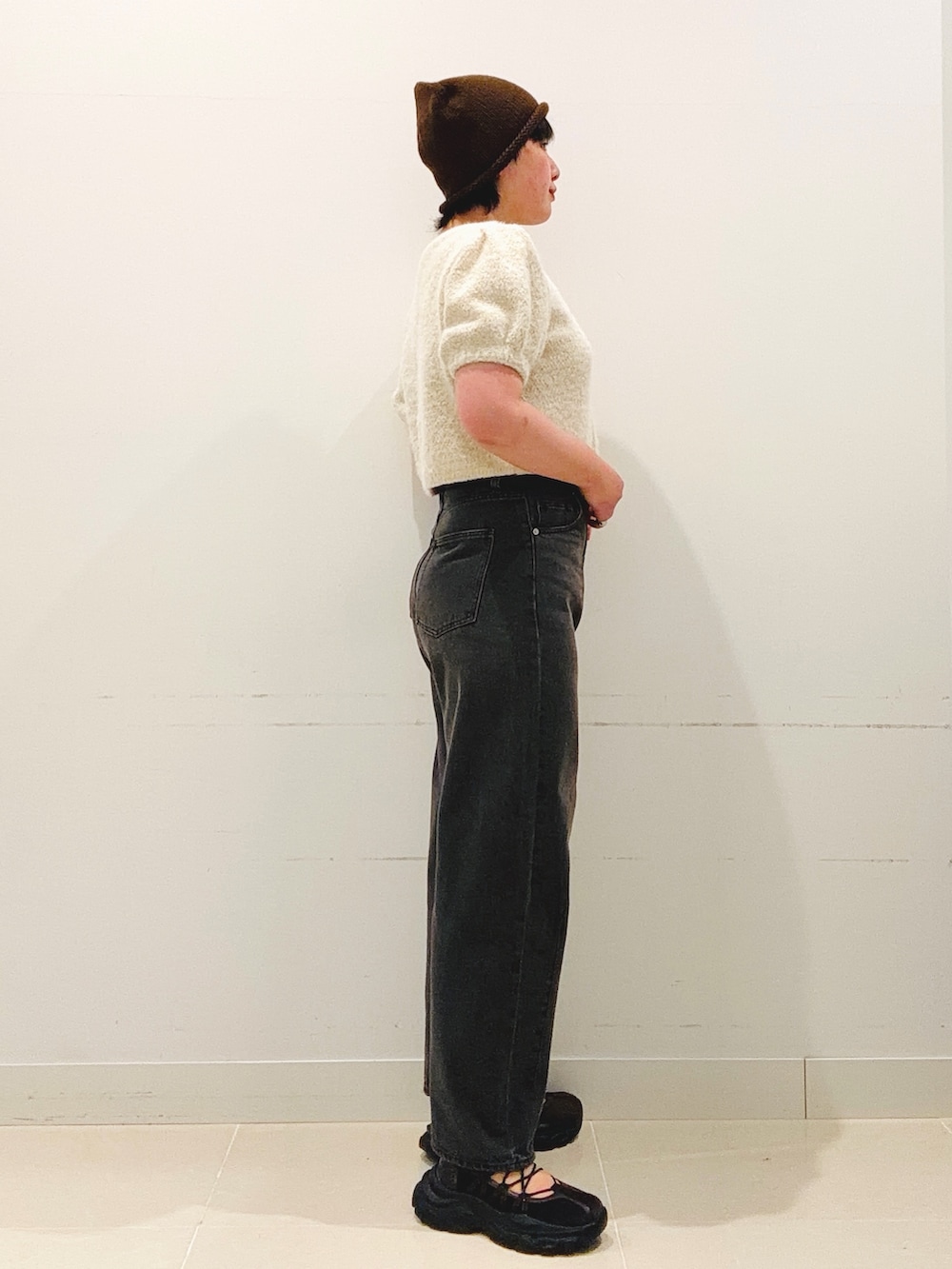 ブラウン系のスニーカー、ホワイト系のニット/セーター、グレー系のデニムパンツを着用したレディースの夏コーディネートの2枚目の写真