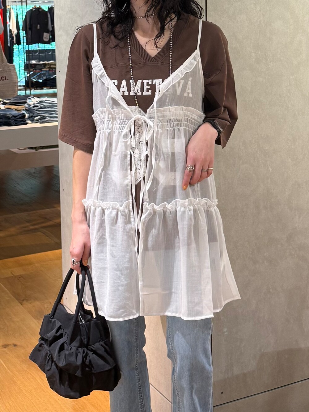ブルー系のデニムパンツ、ホワイト系のベスト、ブラウン系のTシャツ/カットソーを着用したレディースの夏コーディネートの6枚目の写真