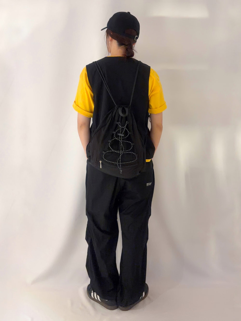 ブラック系のショルダーバッグ、イエロー系のTシャツ/カットソー、ブラック系のキャップを着用したレディースの夏コーディネートの3枚目の写真