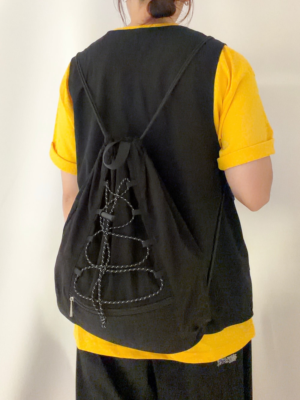 ブラック系のショルダーバッグ、イエロー系のTシャツ/カットソー、ブラック系のキャップを着用したレディースの夏コーディネートの5枚目の写真