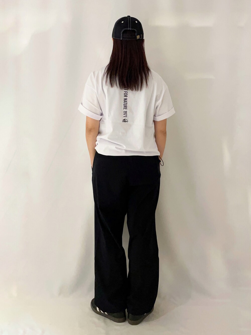 ホワイト系のTシャツ/カットソー、ブラック系のその他パンツ、ブラック系のキャップを着用したレディースの春コーディネートの4枚目の写真