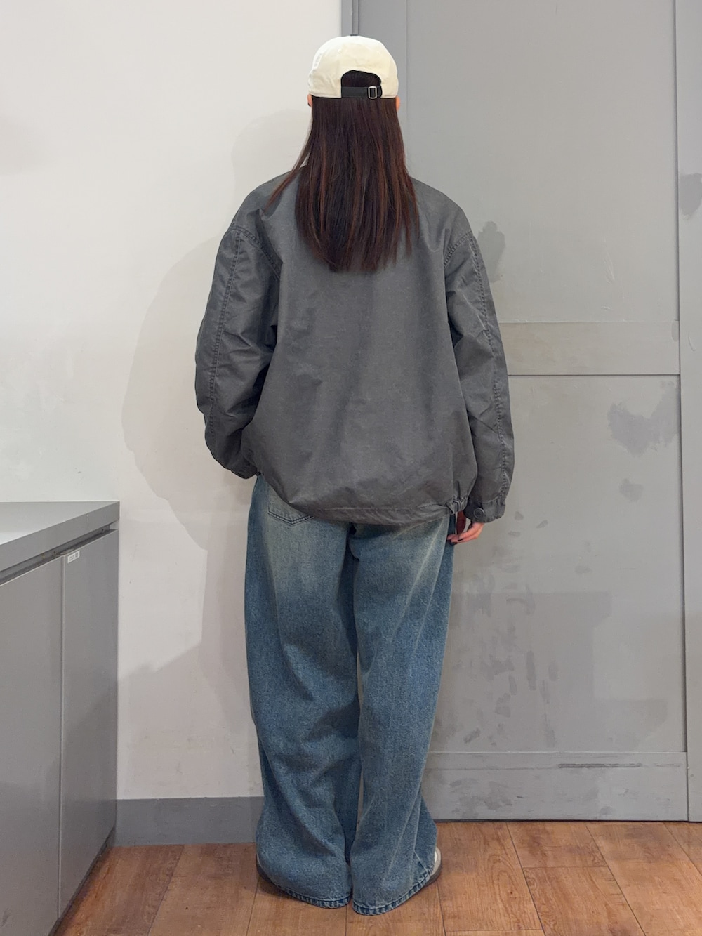 グレー系のミリタリージャケット、グレー系のTシャツ/カットソー、ブルー系のデニムパンツを着用したレディースの秋コーディネートの4枚目の写真