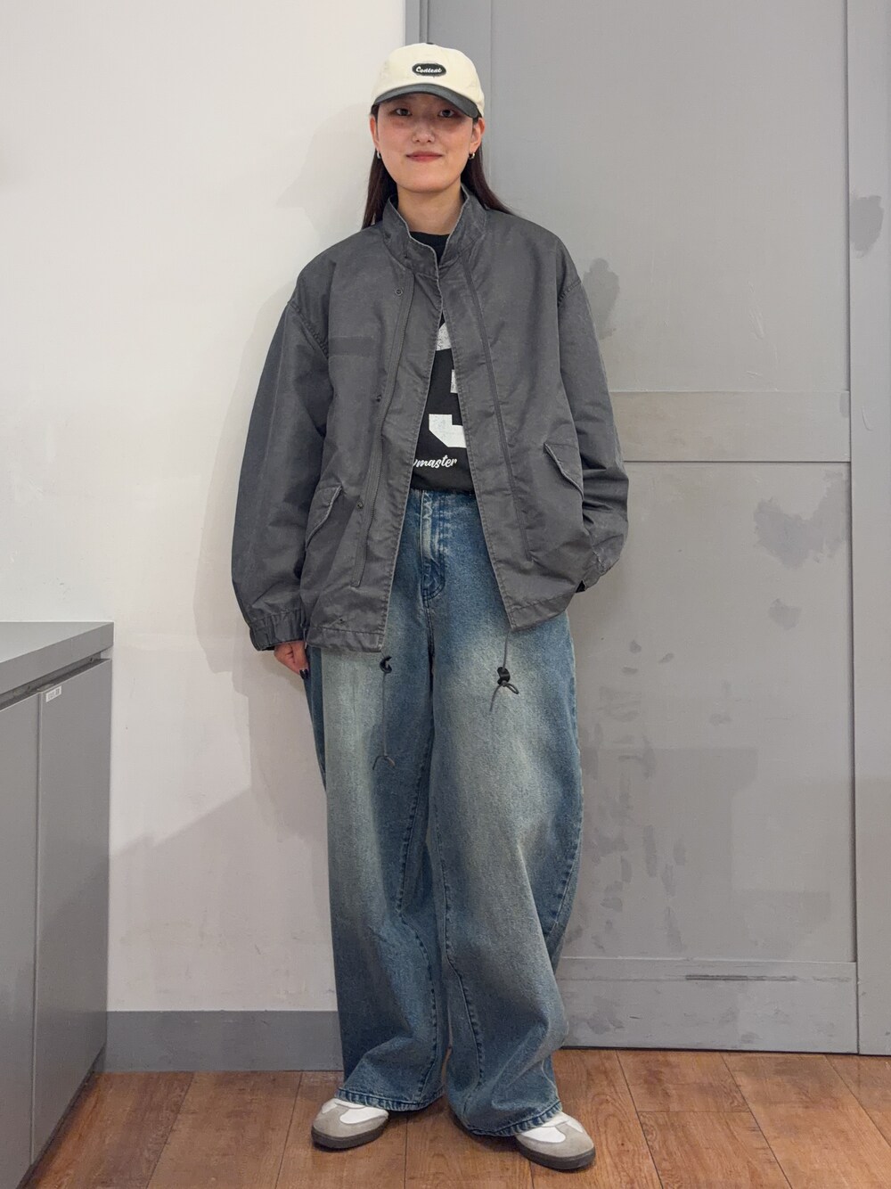 グレー系のミリタリージャケット、グレー系のTシャツ/カットソー、ブルー系のデニムパンツを着用したレディースの秋コーディネートの2枚目の写真