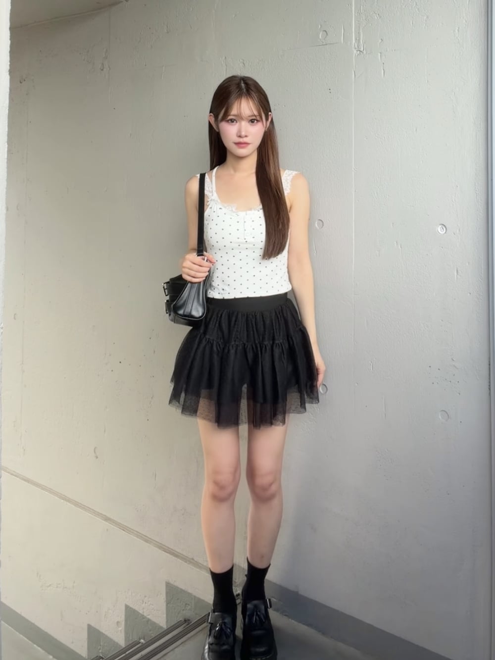ブラック系のスカート、ホワイト系のキャミソールを着用したレディースの夏コーディネートの2枚目の写真