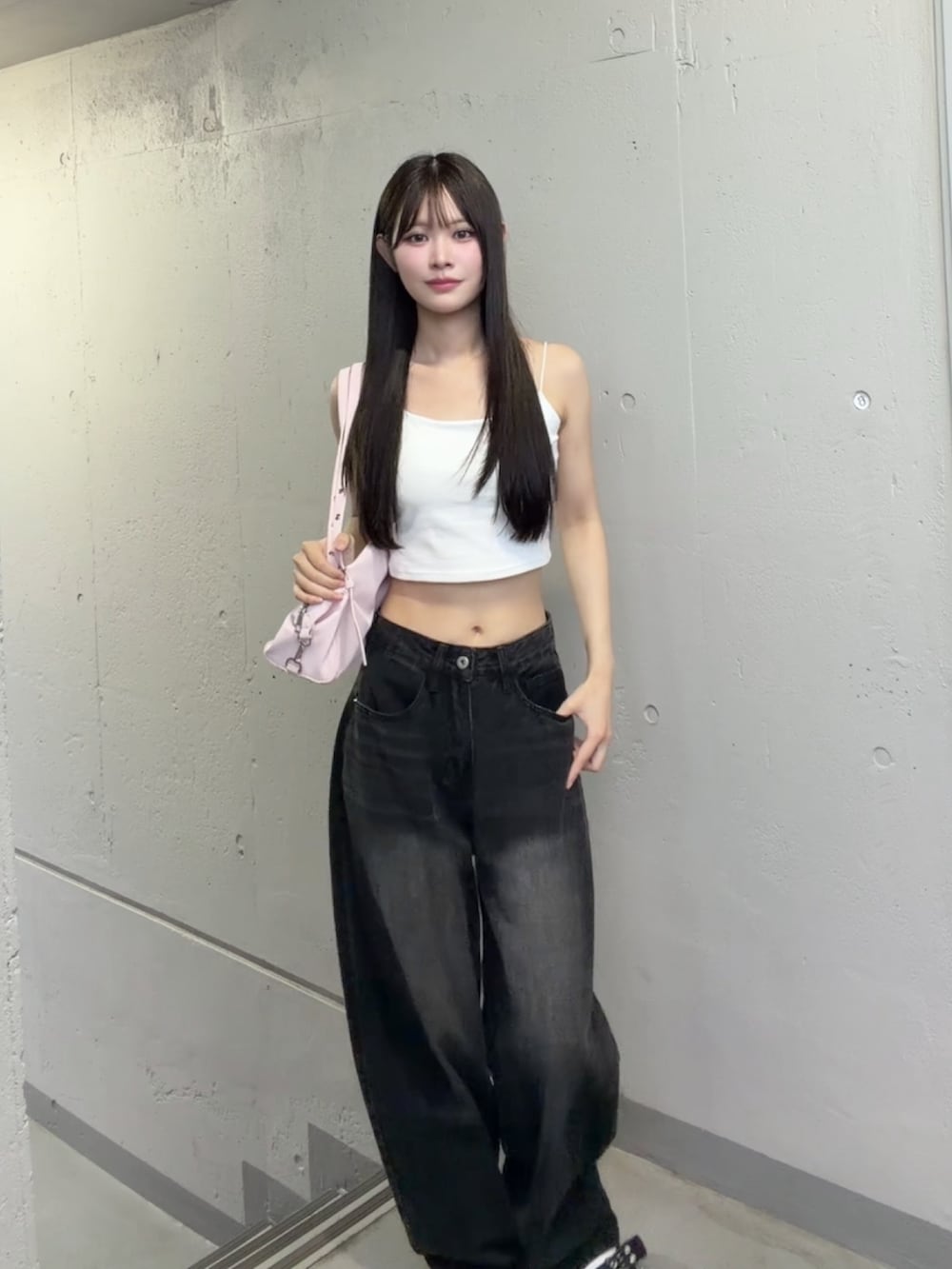 ブラック系のデニムパンツ、ピンク系のショルダーバッグ、ホワイト系のキャミソールを着用したレディースの秋コーディネートの2枚目の写真
