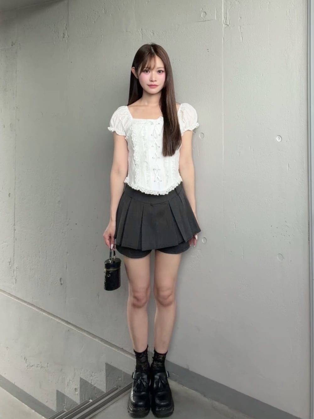 グレー系のスカート、ホワイト系のシャツ/ブラウス、ブラック系のその他シューズを着用したレディースの夏コーディネートの2枚目の写真