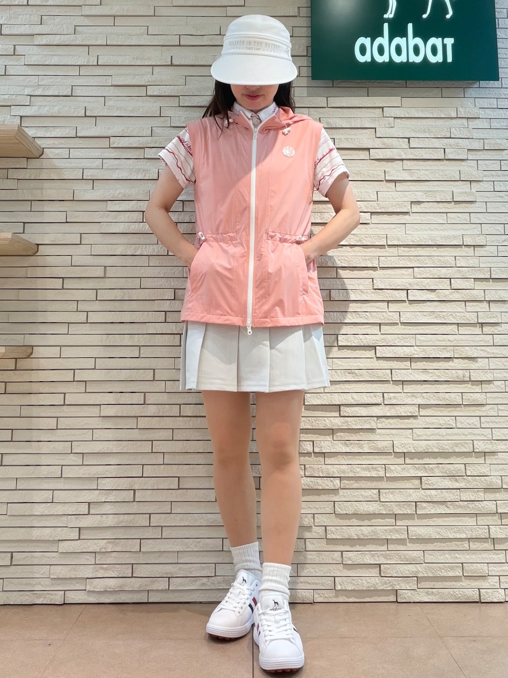 ピンク系のポロシャツ、グレー系のスカート、ピンク系のベストを着用したレディースの夏コーディネートの4枚目の写真