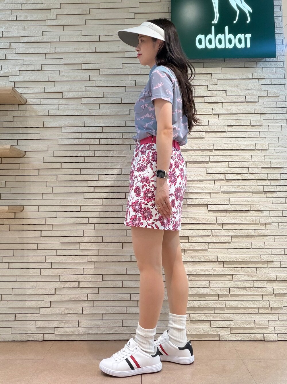 パープル系のポロシャツ、ピンク系のスカート、ブルー系のトートバッグを着用したレディースの夏コーディネートの2枚目の写真