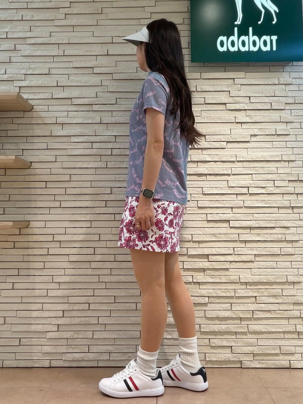 パープル系のポロシャツ、ピンク系のスカート、ブルー系のトートバッグを着用したレディースの夏コーディネートの5枚目の写真