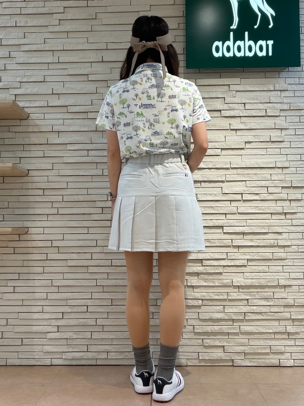 ホワイト系のポロシャツ、グレー系のスカート、ベージュ系のトートバッグを着用したレディースの夏コーディネートの3枚目の写真