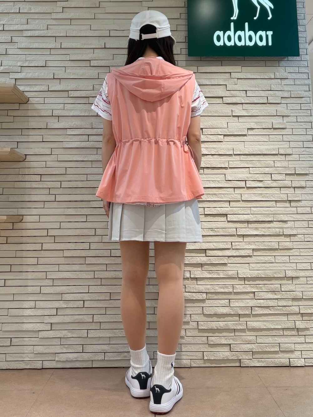 ピンク系のポロシャツ、グレー系のスカート、ピンク系のベストを着用したレディースの夏コーディネートの3枚目の写真