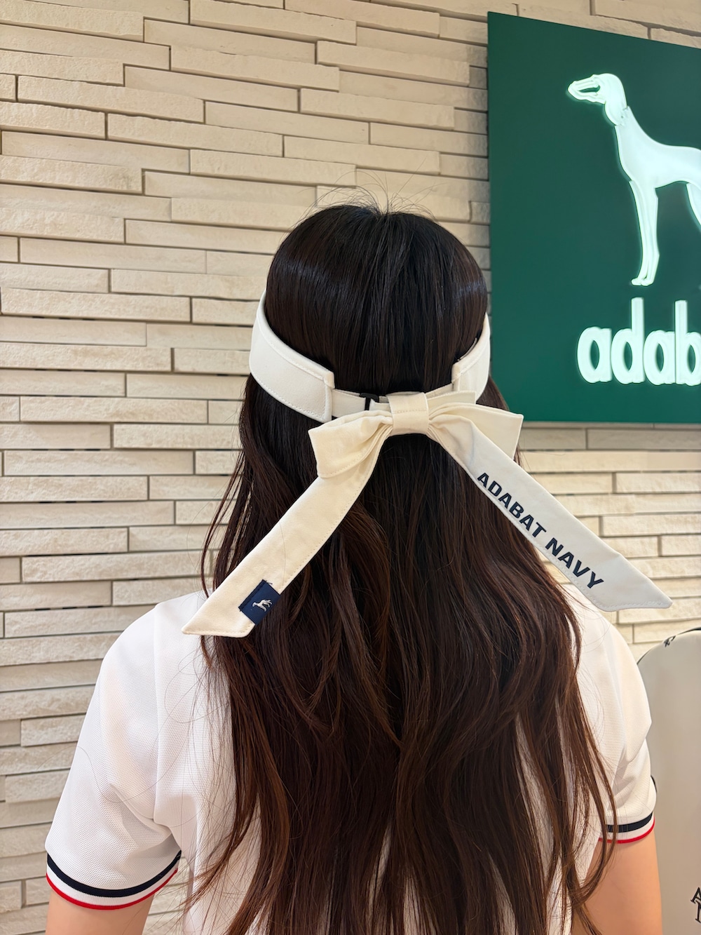 ホワイト系のポロシャツ、グレー系のスカート、ホワイト系のサンバイザーを着用したレディースの夏コーディネートの5枚目の写真