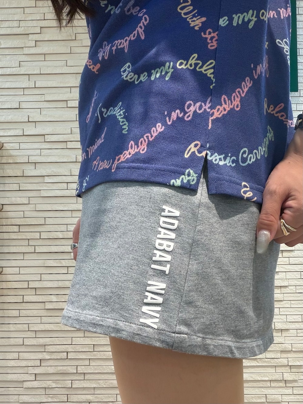 ブルー系のポロシャツ、グレー系のスカート、グレー系のトートバッグを着用したレディースの夏コーディネートの7枚目の写真