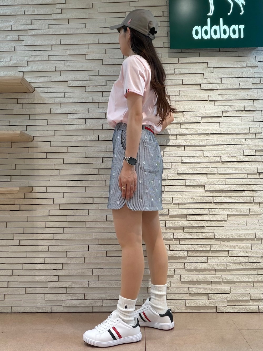 ピンク系のTシャツ/カットソー、ホワイト系のスカート、ホワイト系のゴルフグッズを着用したレディースの夏コーディネートの2枚目の写真
