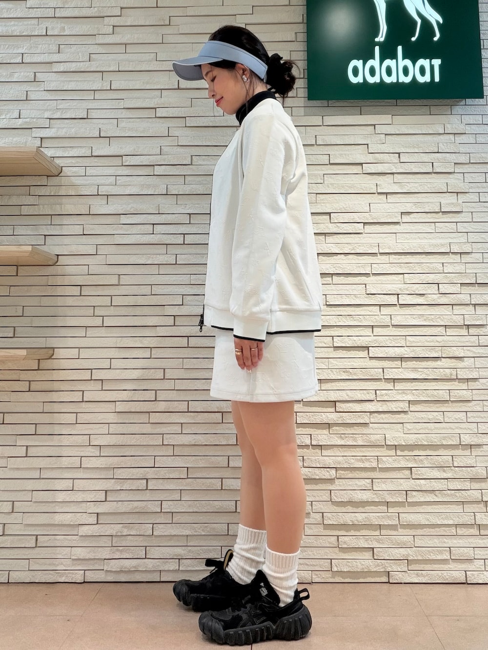 ホワイト系のブルゾン、ブラック系のTシャツ/カットソー、ホワイト系のスカートを着用したレディースの秋コーディネートの2枚目の写真