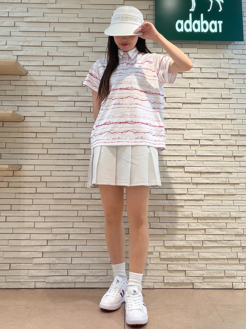 ピンク系のポロシャツ、グレー系のスカート、ピンク系のベストを着用したレディースの夏コーディネートの5枚目の写真