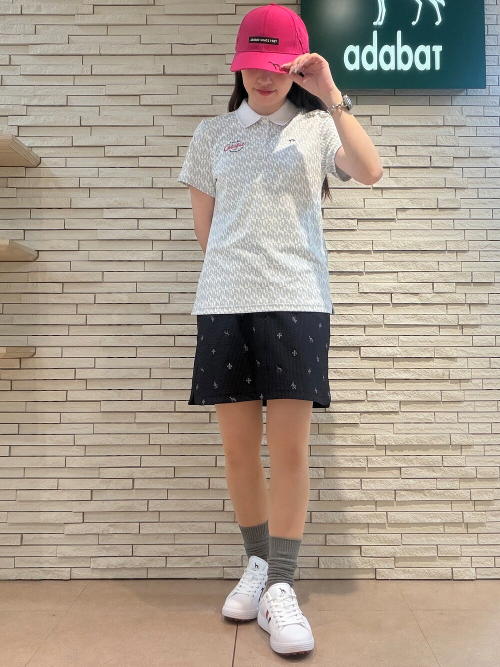 グレー系のポロシャツ、ブルー系のスカート、ブルー系のトートバッグを着用したレディースの夏コーディネートの5枚目の写真