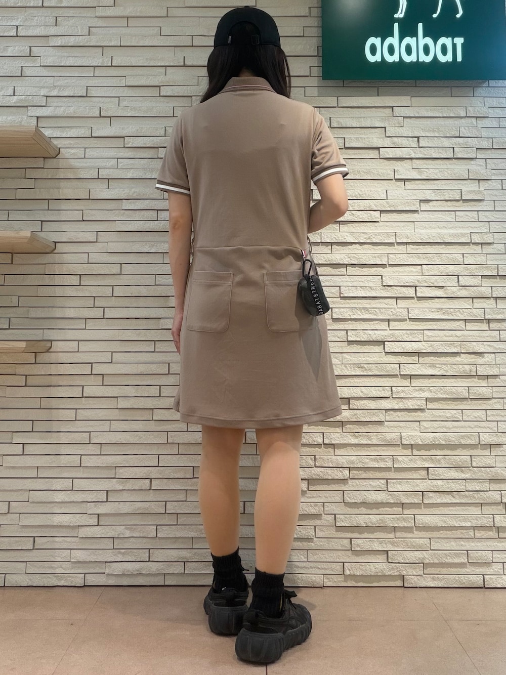ベージュ系のワンピース、ブラック系のキャップ、ブラック系のポーチを着用したレディースの夏コーディネートの3枚目の写真