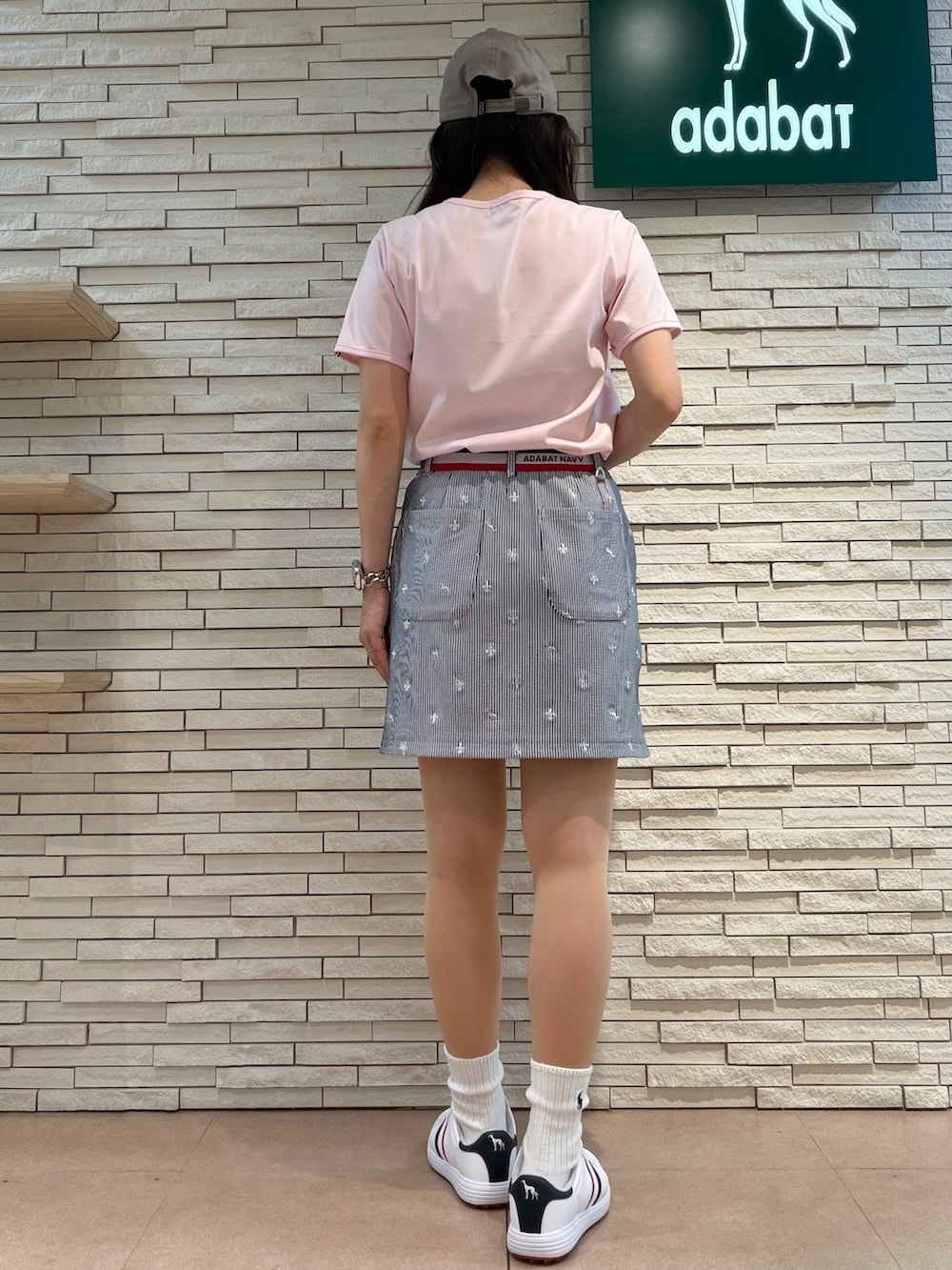 ピンク系のTシャツ/カットソー、ホワイト系のスカート、ホワイト系のゴルフグッズを着用したレディースの夏コーディネートの3枚目の写真