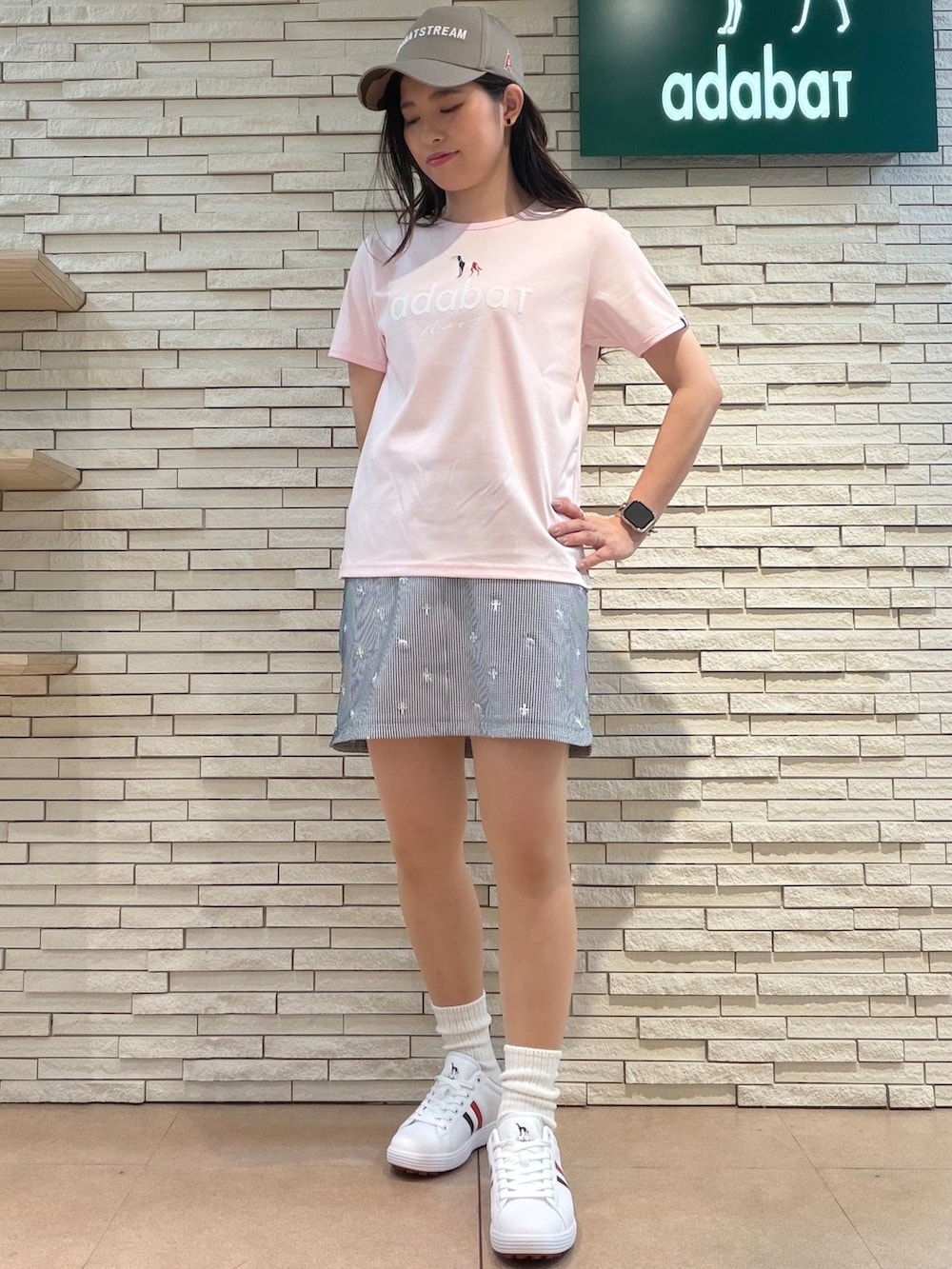 ピンク系のTシャツ/カットソー、ホワイト系のスカート、ホワイト系のゴルフグッズを着用したレディースの夏コーディネートの4枚目の写真
