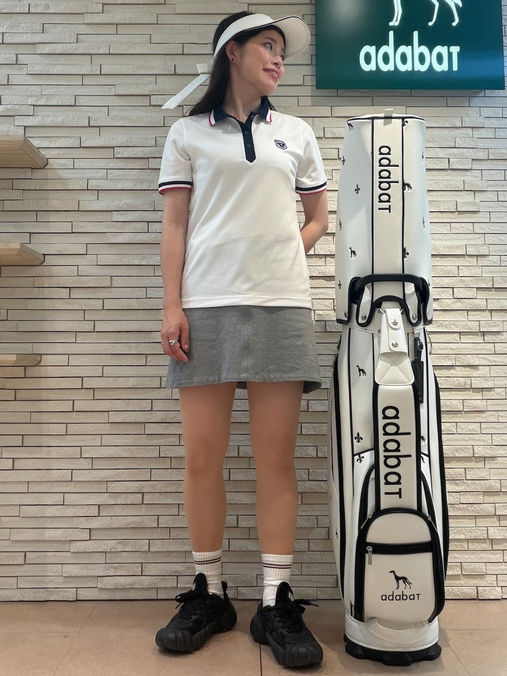 ホワイト系のポロシャツ、グレー系のスカート、ホワイト系のサンバイザーを着用したレディースの夏コーディネートの4枚目の写真
