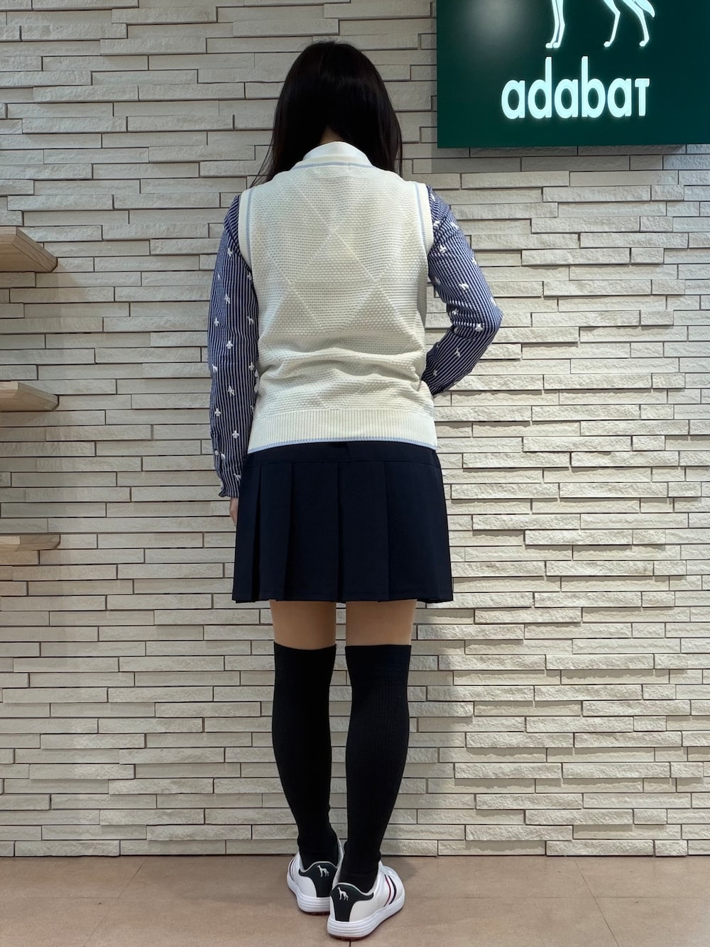 ホワイト系のベスト、ホワイト系のTシャツ/カットソー、ブルー系のスカートを着用したレディースの秋コーディネートの3枚目の写真