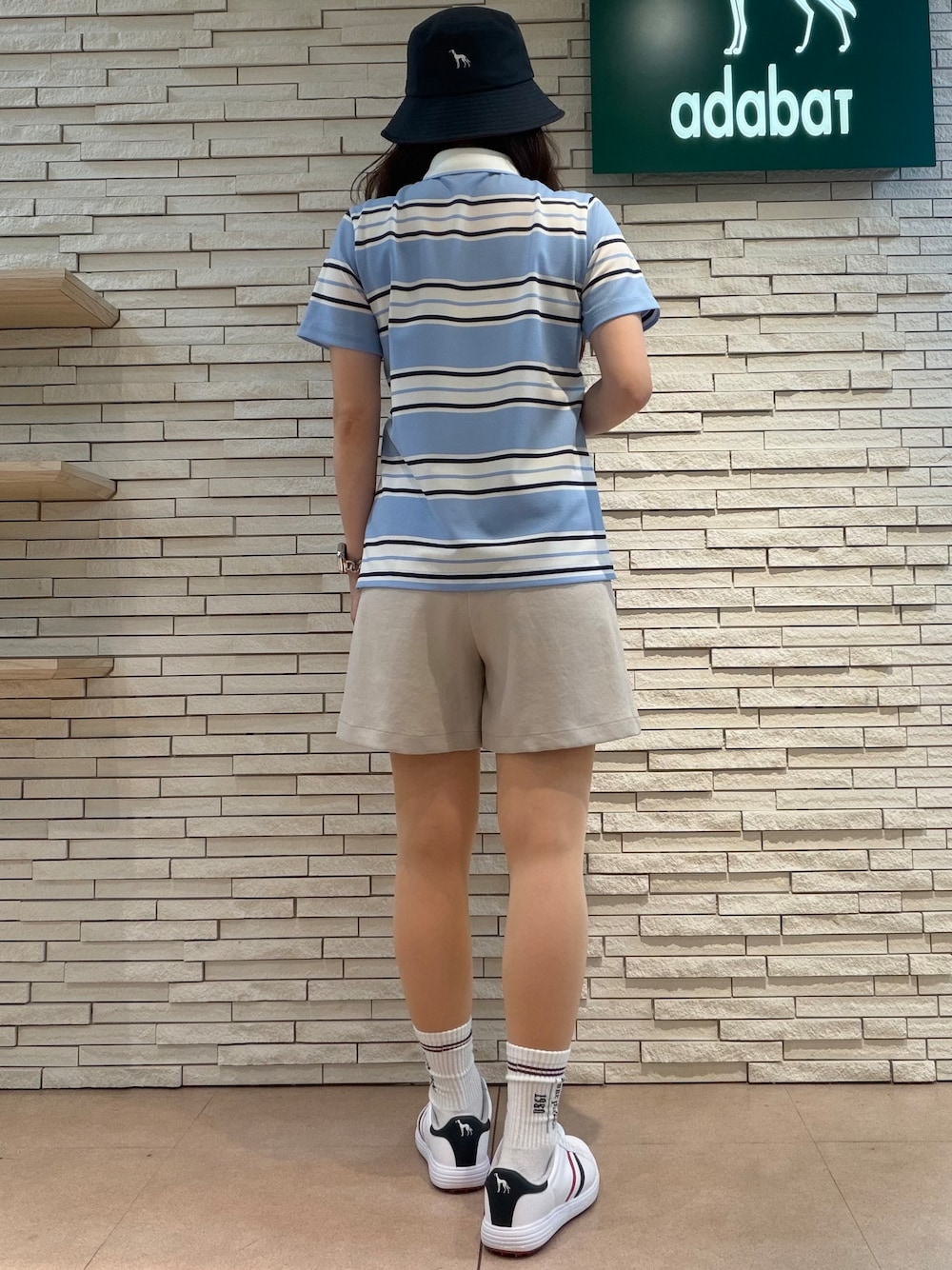 ブルー系のポロシャツ、ベージュ系のその他パンツ、ブルー系のトートバッグを着用したレディースの夏コーディネートの3枚目の写真