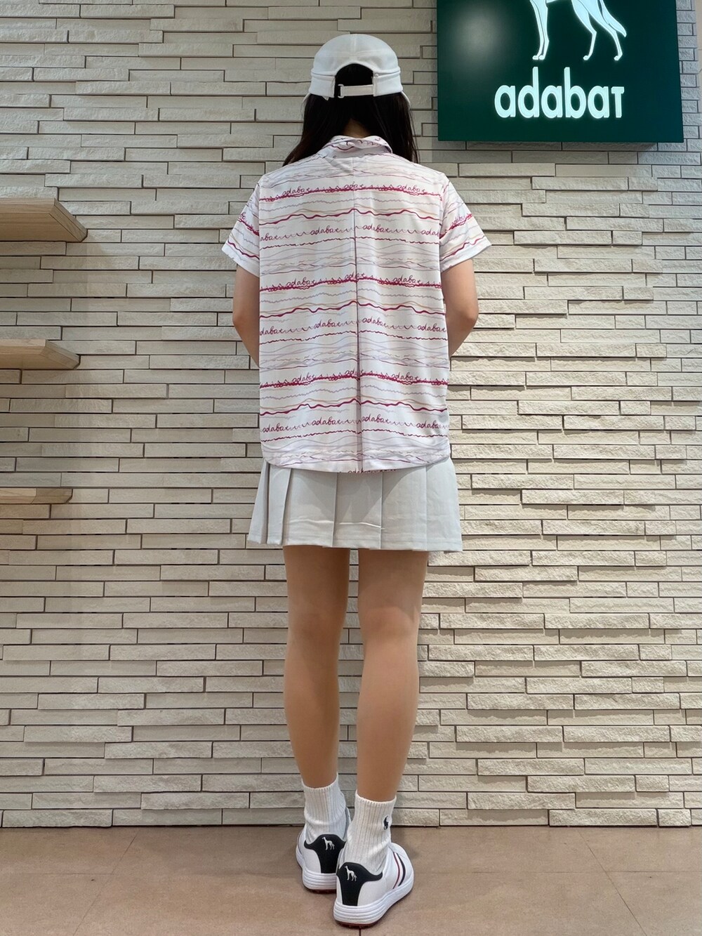 ピンク系のポロシャツ、グレー系のスカート、ピンク系のベストを着用したレディースの夏コーディネートの7枚目の写真