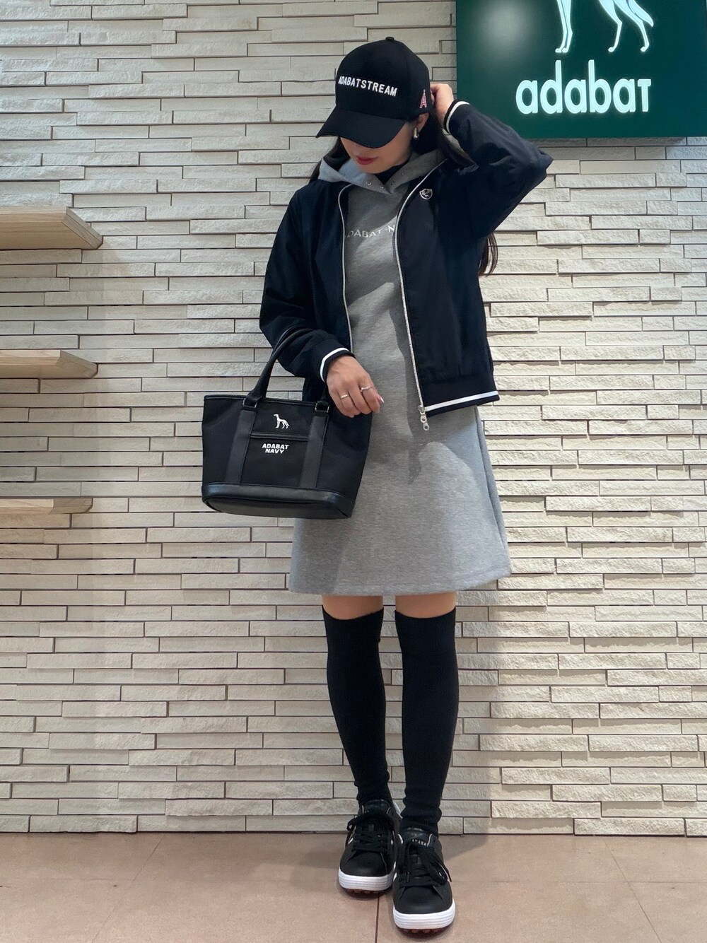 グレー系のワンピース、ブルー系のブルゾン、ブラック系のトートバッグを着用したレディースの秋コーディネートの5枚目の写真
