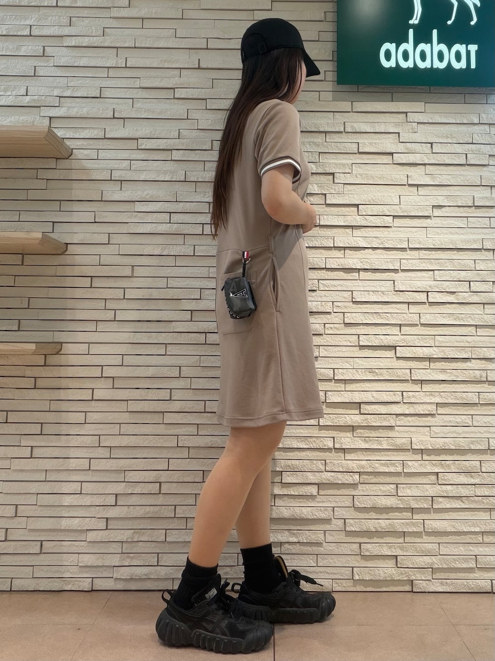 ベージュ系のワンピース、ブラック系のキャップ、ブラック系のポーチを着用したレディースの夏コーディネートの2枚目の写真