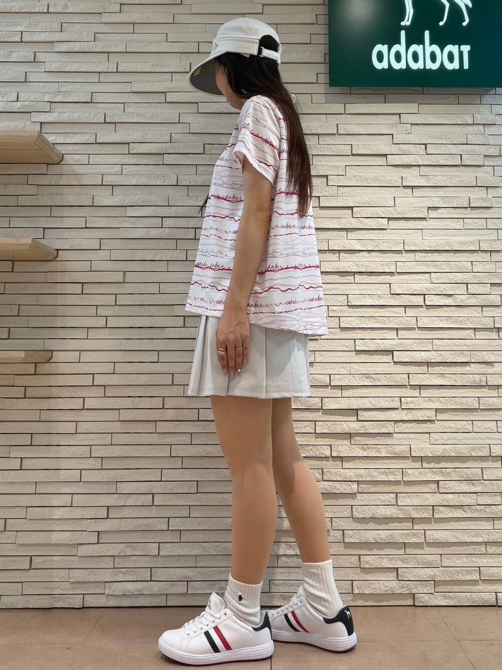ピンク系のポロシャツ、グレー系のスカート、ピンク系のベストを着用したレディースの夏コーディネートの6枚目の写真
